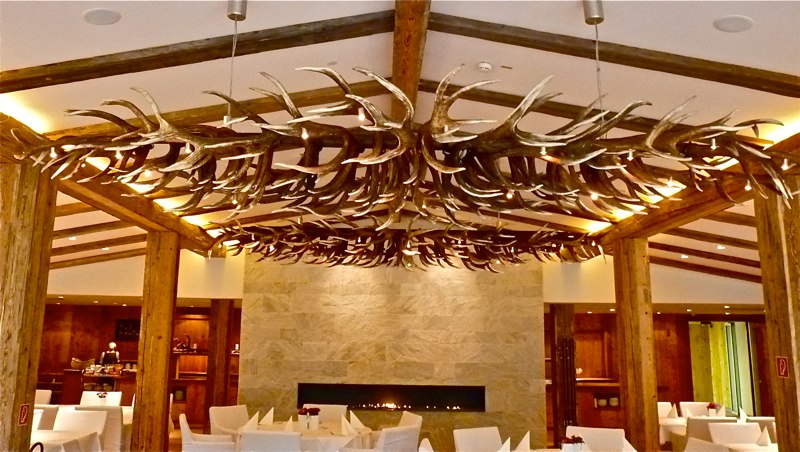 Geweihlüster mit Lichtspots über den Tischen des Restaurants